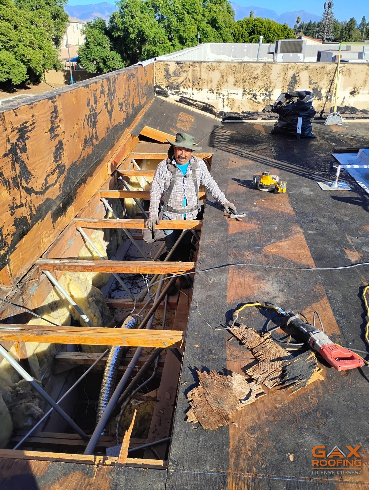 Cuadrilla de GAX Roofing instalando estructura nueva en el techo plano de un edificio comercial de Redlands despu&eacute;s de cortar las secciones podridas