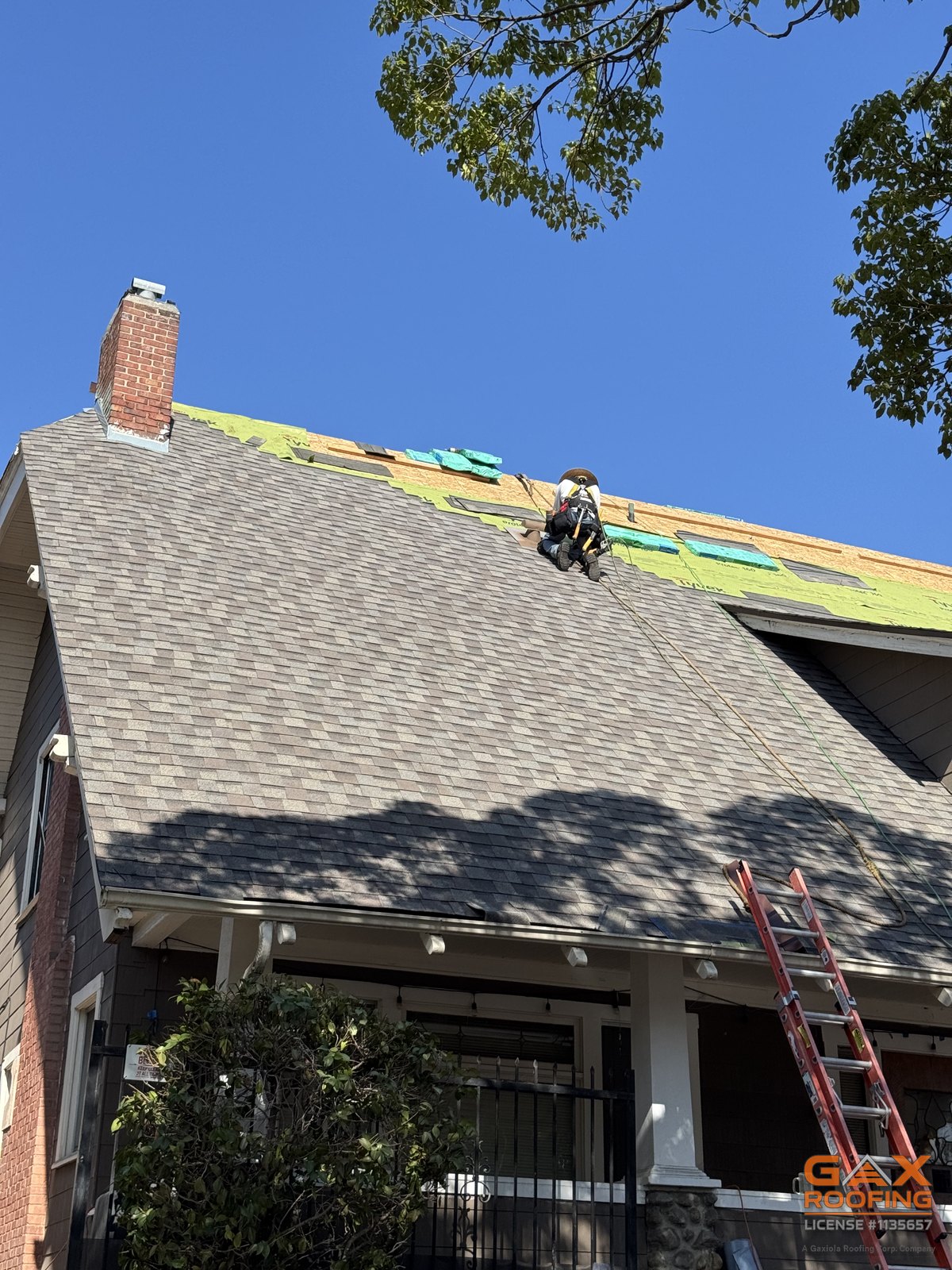 Cuadrilla de GAX Roofing instalando teja arquitectónica GAF en una casa de dos pisos