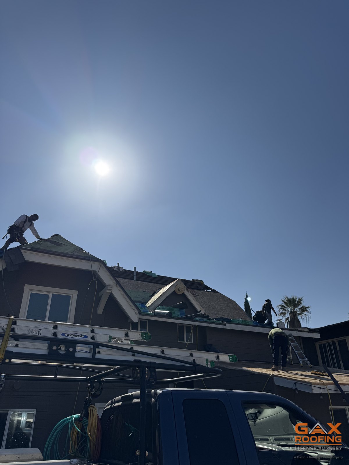Techadores trabajando la cumbrera de una casa de dos pisos durante un reemplazo con teja GAF