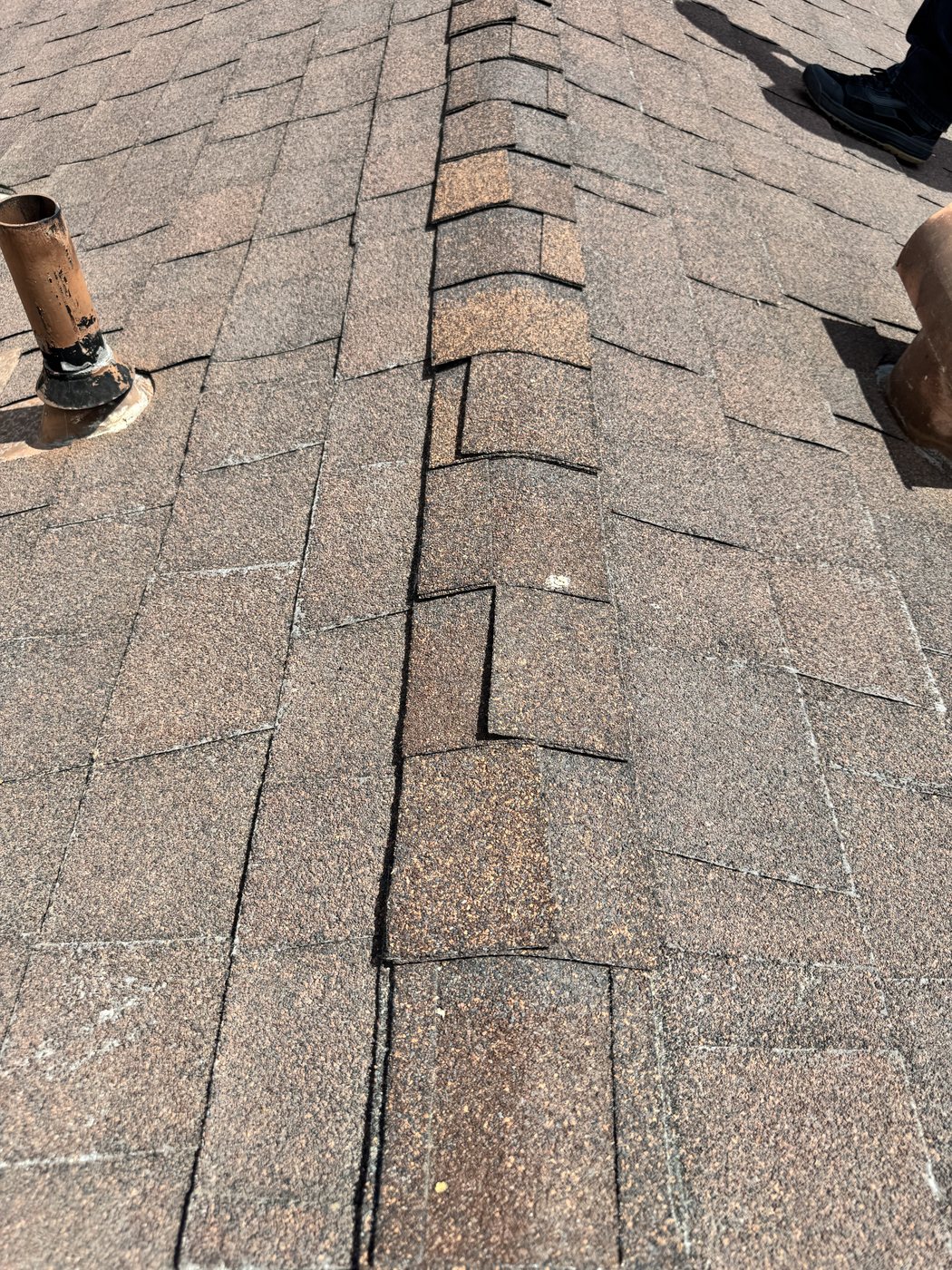 Cut shingle ridge pieces lifting along the ridge line on a Jurupa Valley roof
