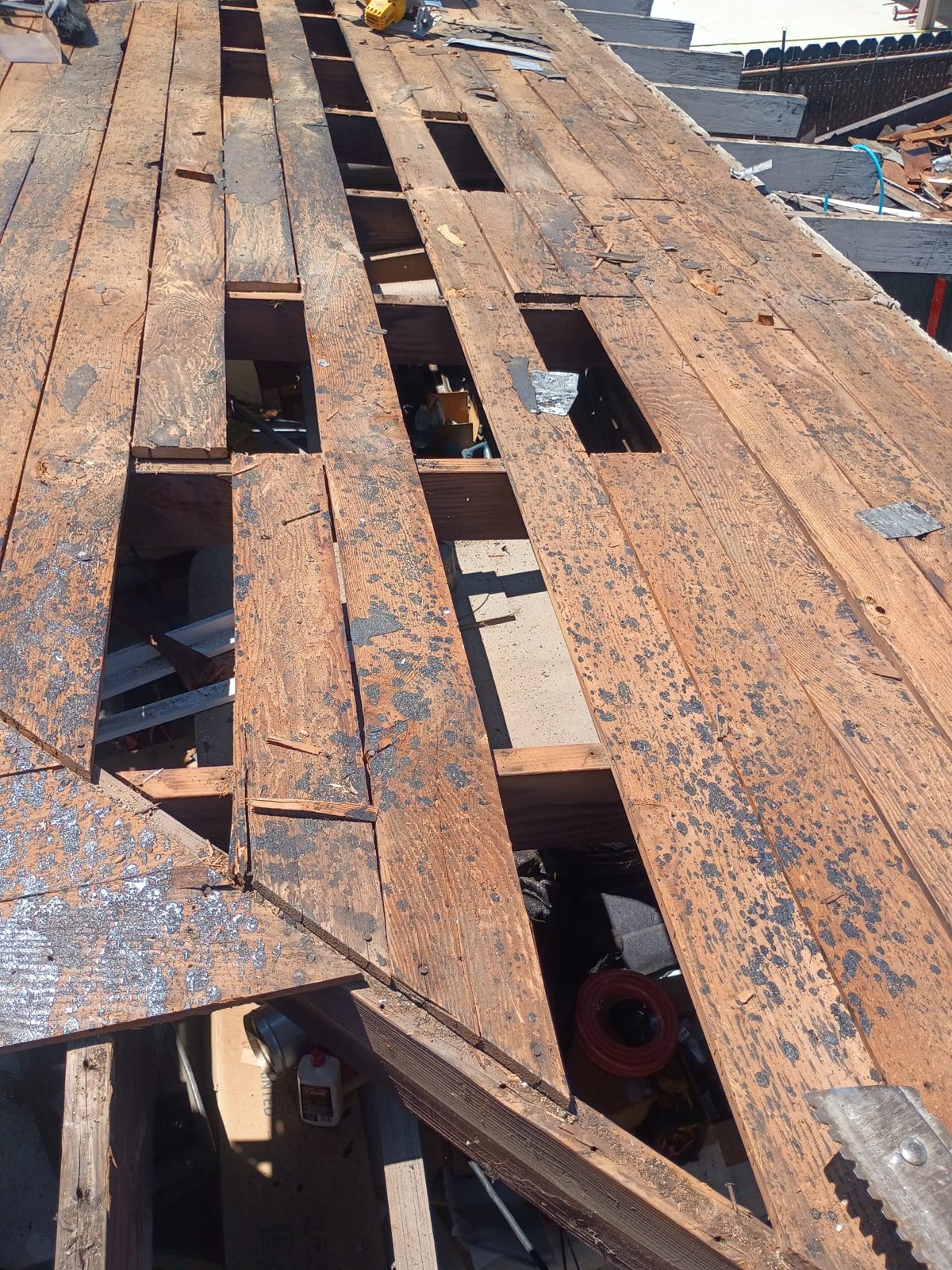 Sección de deck podrida abierta hasta la estructura durante un cambio de techo de GAX Roofing