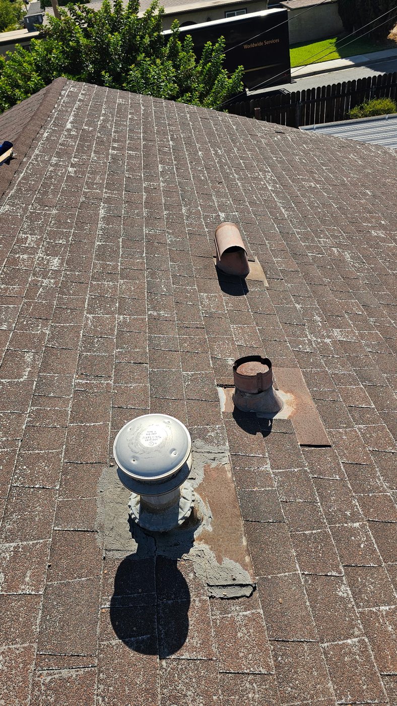 Worn shingles and aged roof vents with fiberglass showing through on a Riverside roof