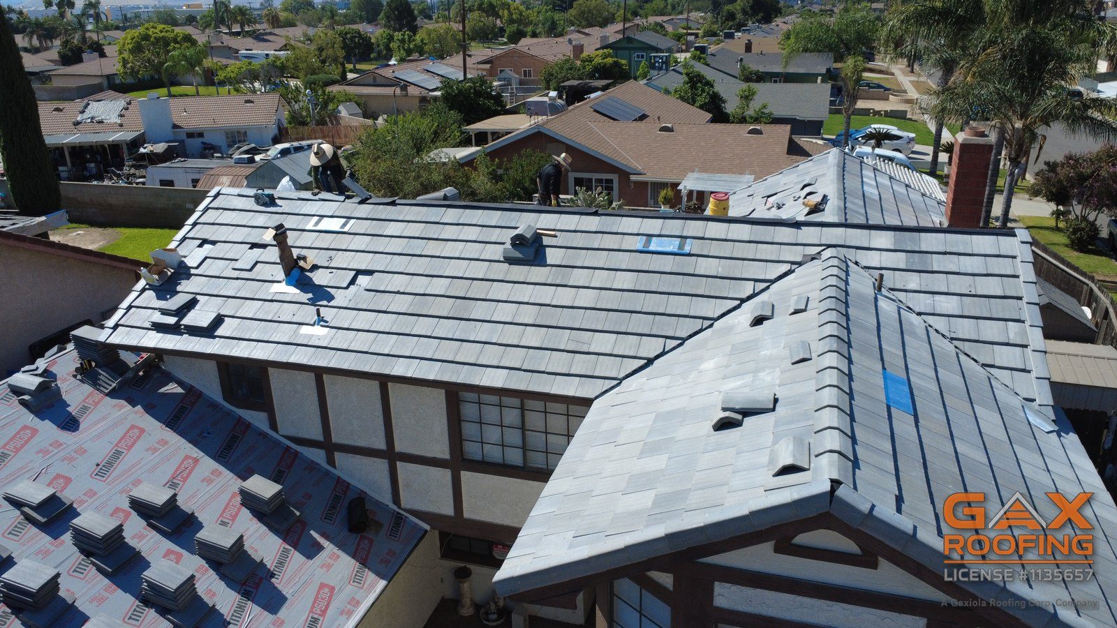 Cuadrilla de GAX Roofing instalando teja plana de concreto nueva sobre papel fresco en Bloomington CA
