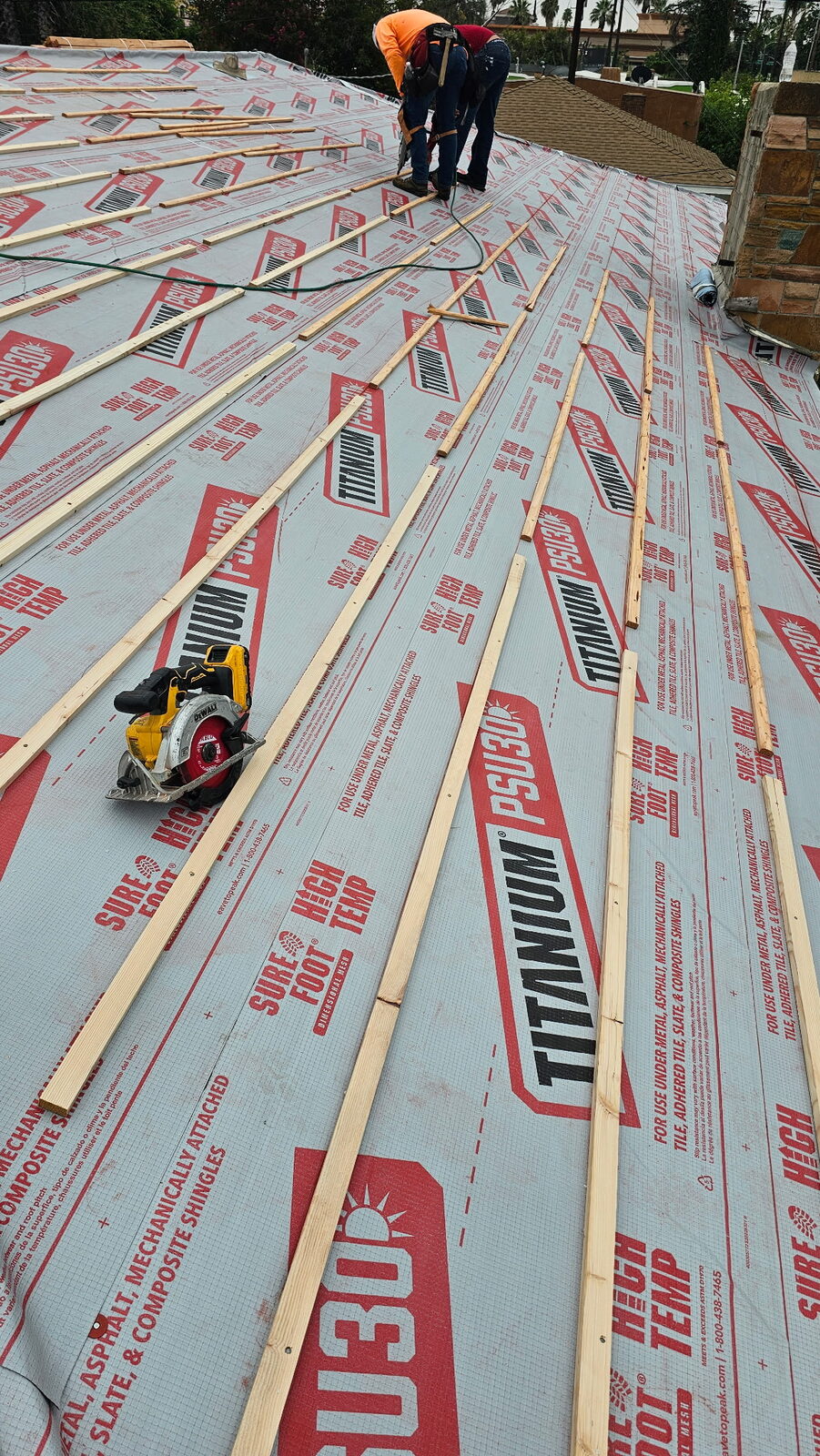 Equipo de GAX Roofing instalando bajo-tejas sintético en un techo