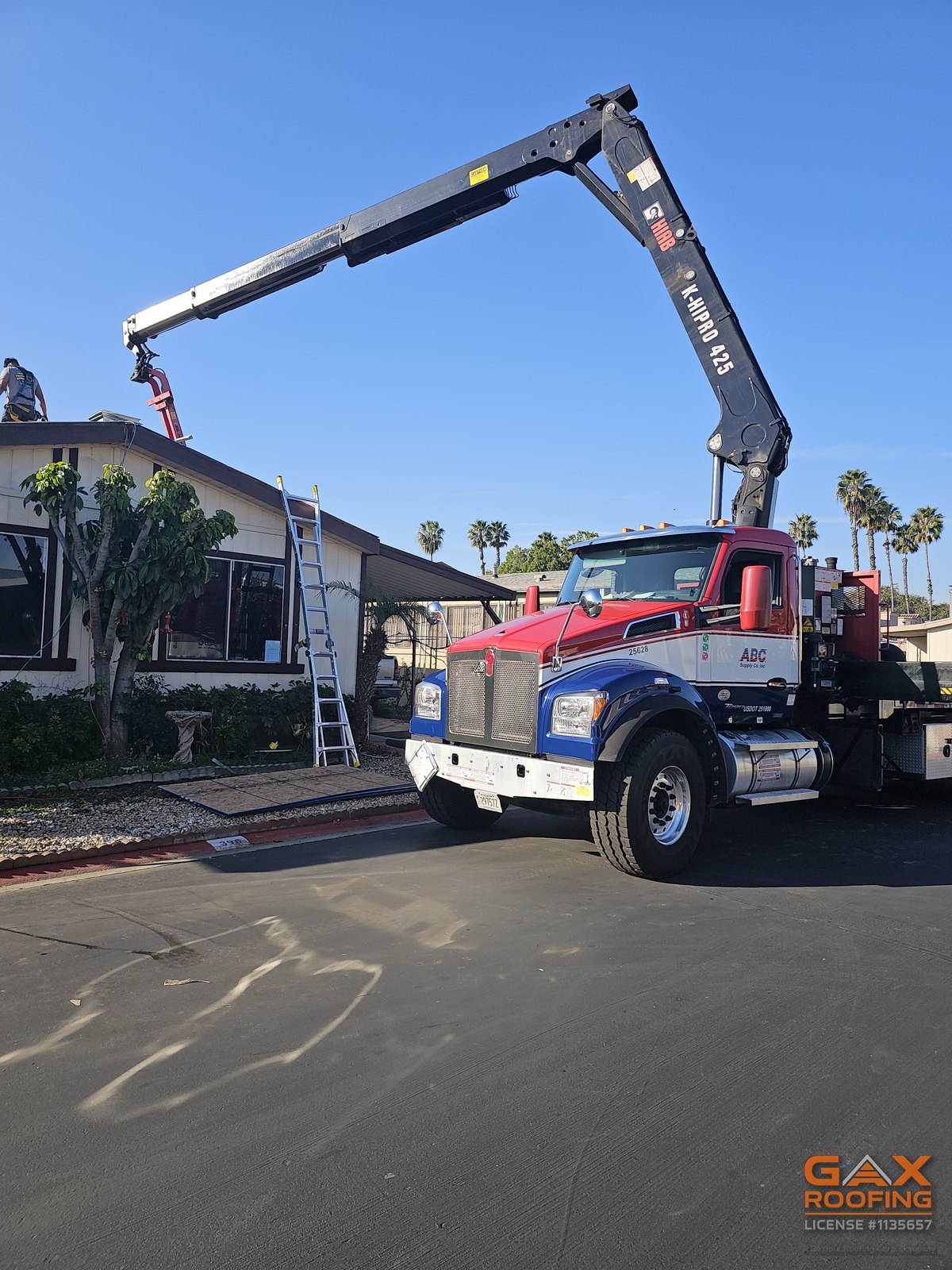 Crane truck delivering roofing materials to a mobile home roof replacement in a Huntington Beach park
