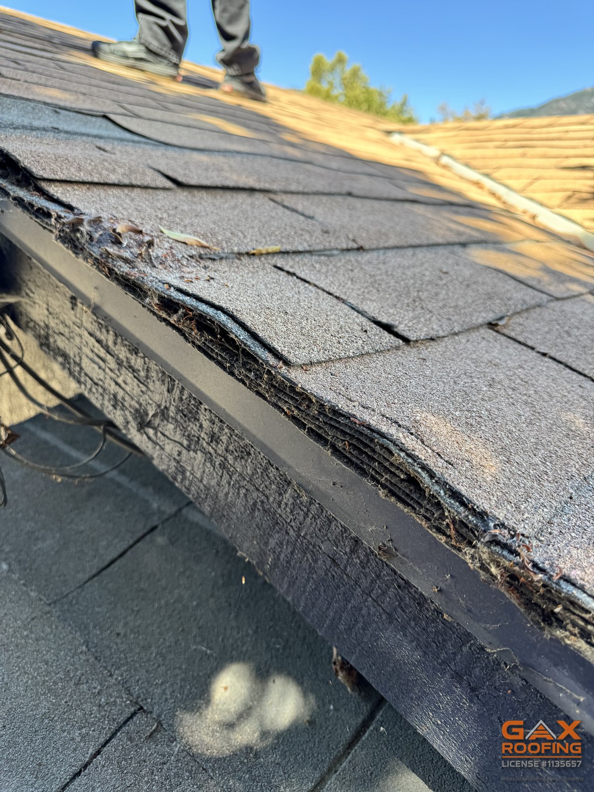 Rake edge of a Highland CA roof during a GAX Roofing inspection showing three or more layers of asphalt shingles stacked with no drip edge