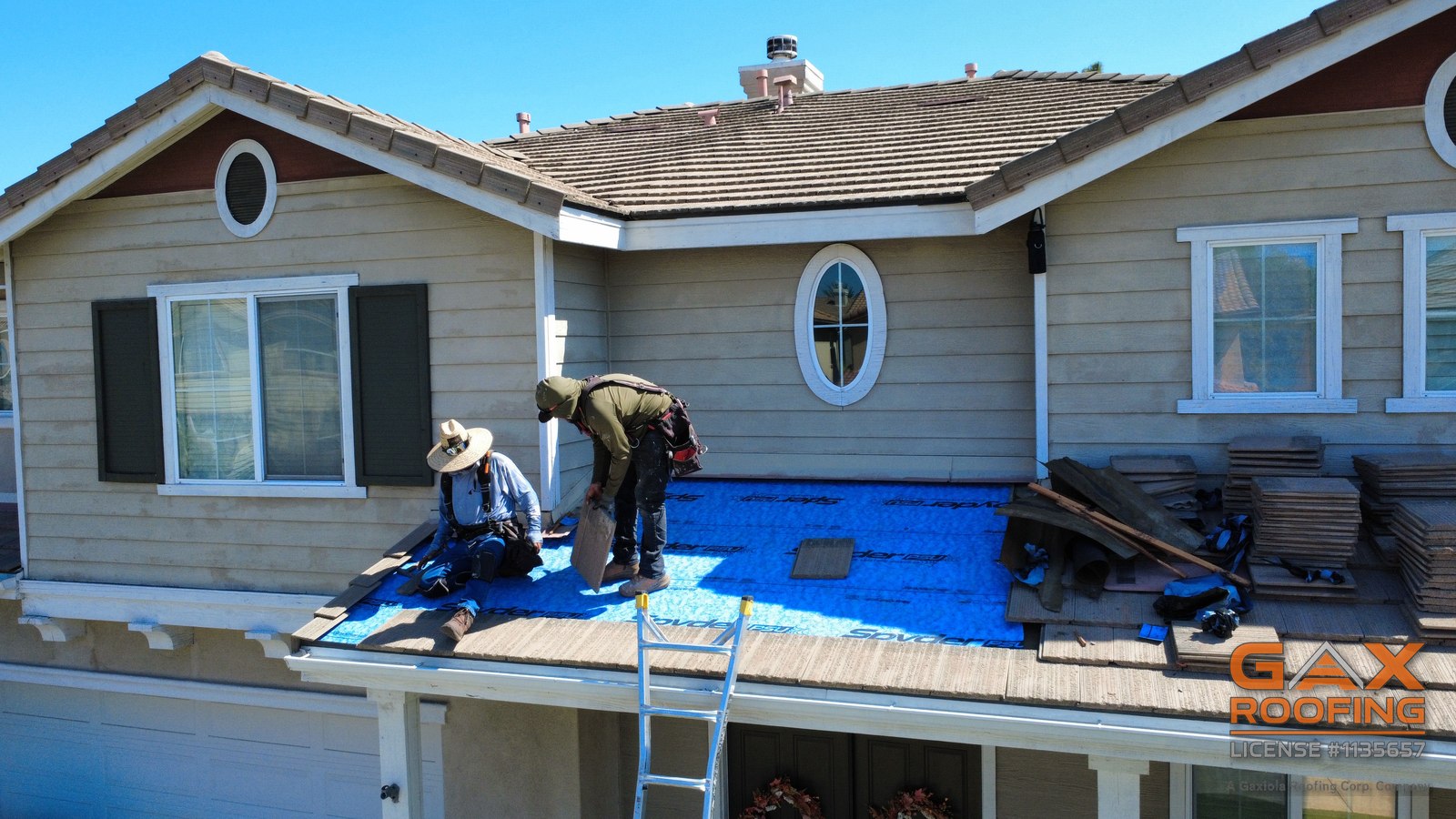 Cuadrilla de GAX Roofing recolocando teja de concreto plana sobre membrana autoadherible nueva en la secci&oacute;n del techo del patio de una casa en Huntington Beach
