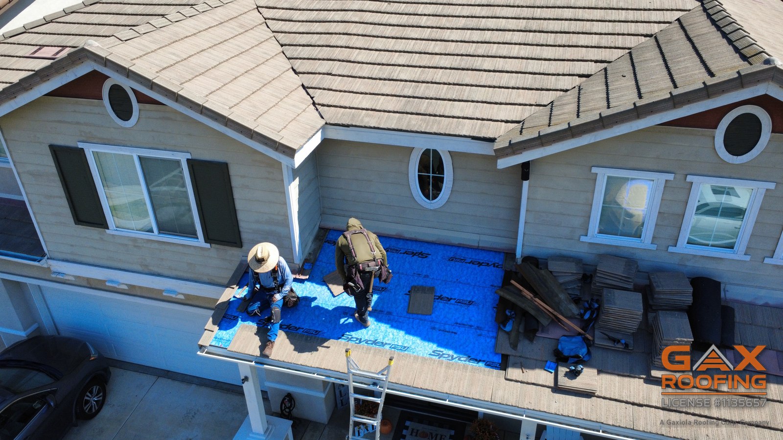 Casa de dos pisos en Huntington Beach con la secci&oacute;n del techo del patio abierta para una reparaci&oacute;n de teja, cuadrilla en el techo y escalera en el alero
