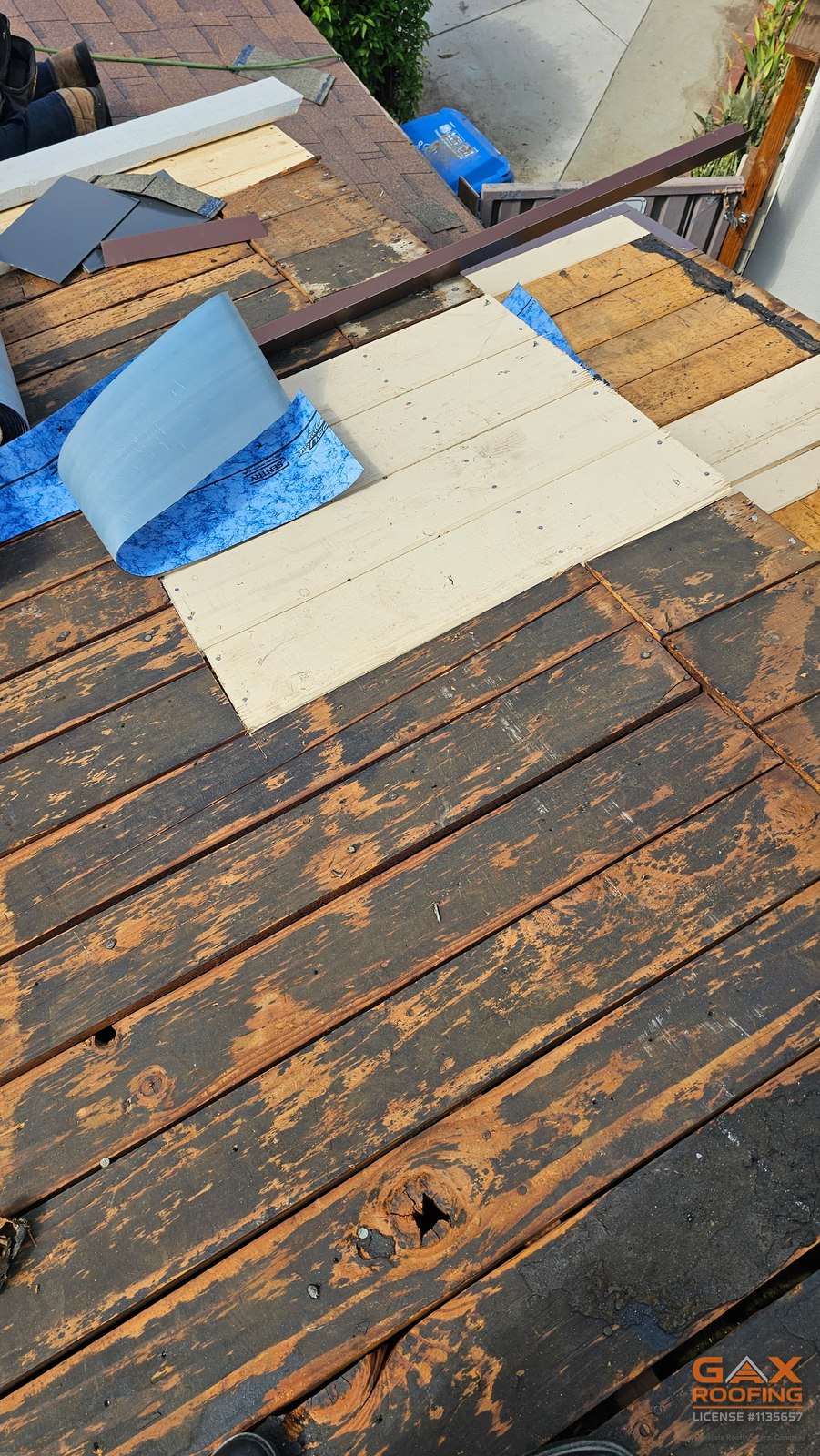 Cubierta de tablones original a la vista al retirar el techo viejo en un reemplazo de techo en West Covina, con los tablones que necesitaban cambio ya reemplazados por madera nueva