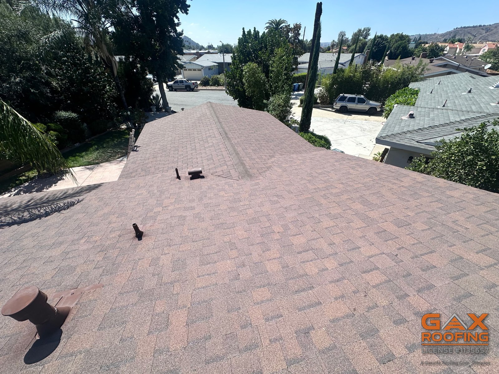 Finished brown architectural shingle roof in West Covina, CA with a ridge vent and vents painted to match, view along the ridge