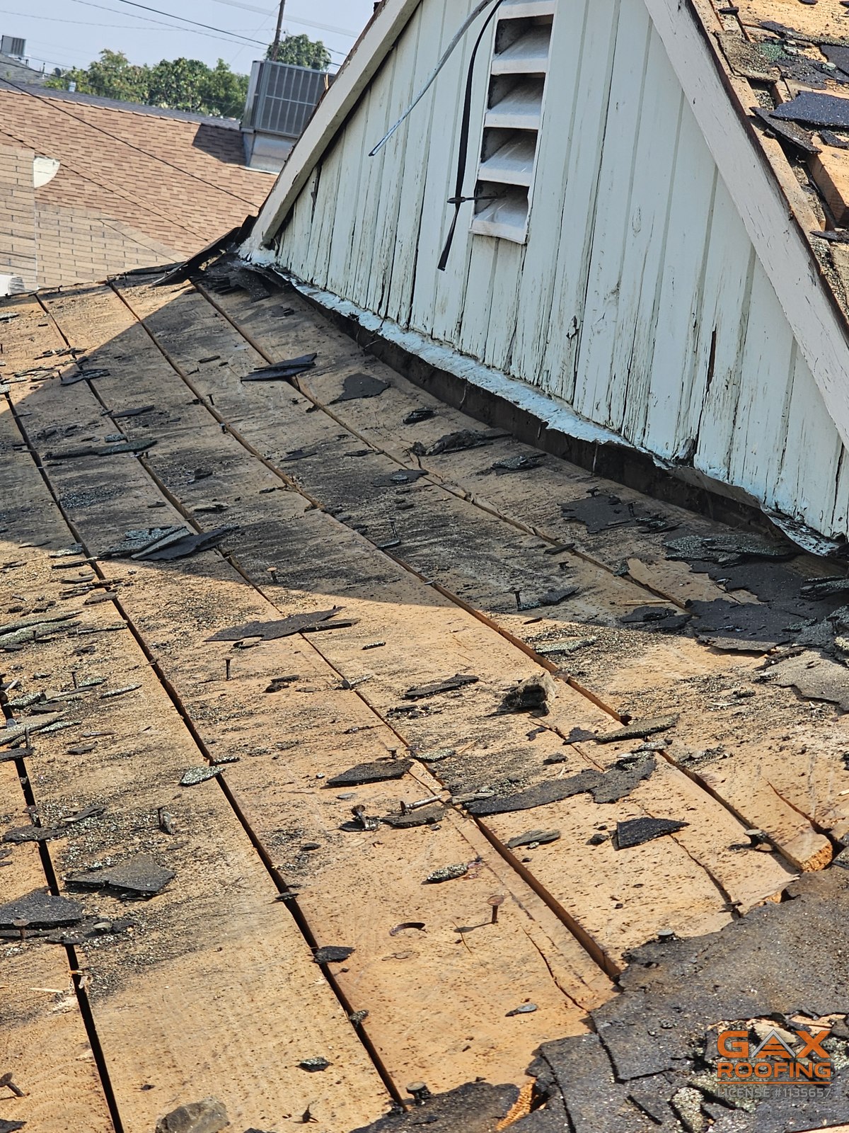 Roof tear-off in progress in San Antonio Heights, California, old shingles stripped back to the original skip sheathing with debris still on the slope