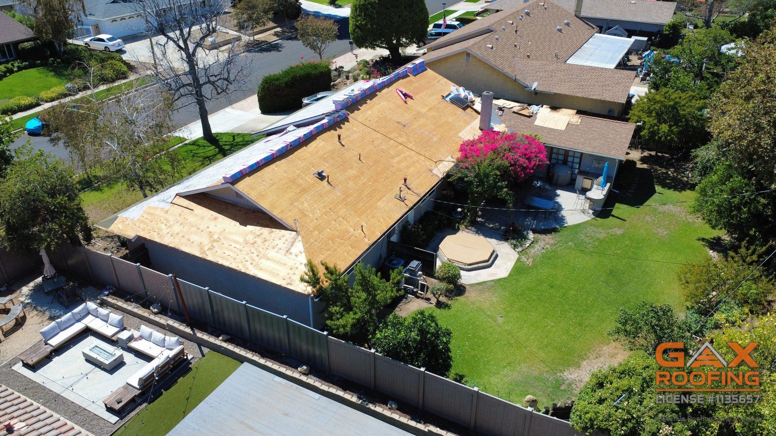 Back of a Rancho Cucamonga home during a shingle roof replacement, roof deck exposed and underlayment going on, drone view