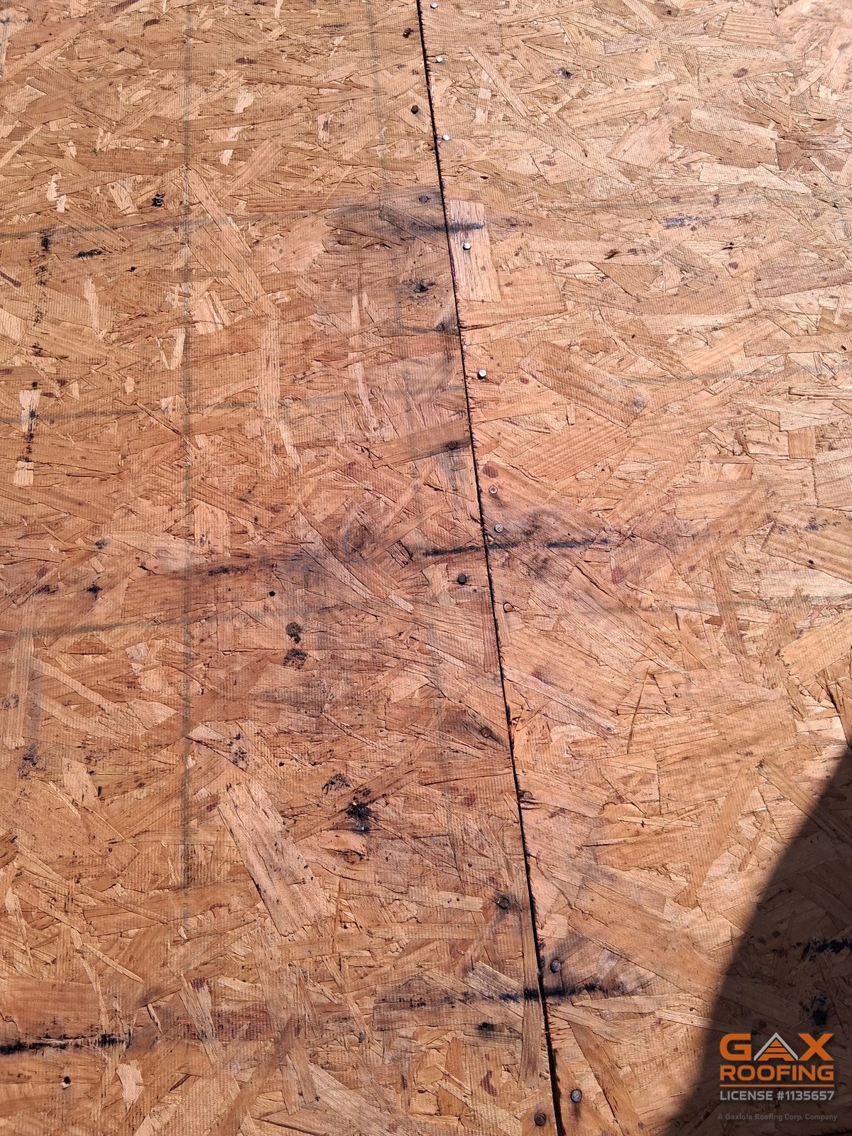 Roof deck with water staining along the seams, exposed during a tile roof repair under solar panels in Rancho Cucamonga