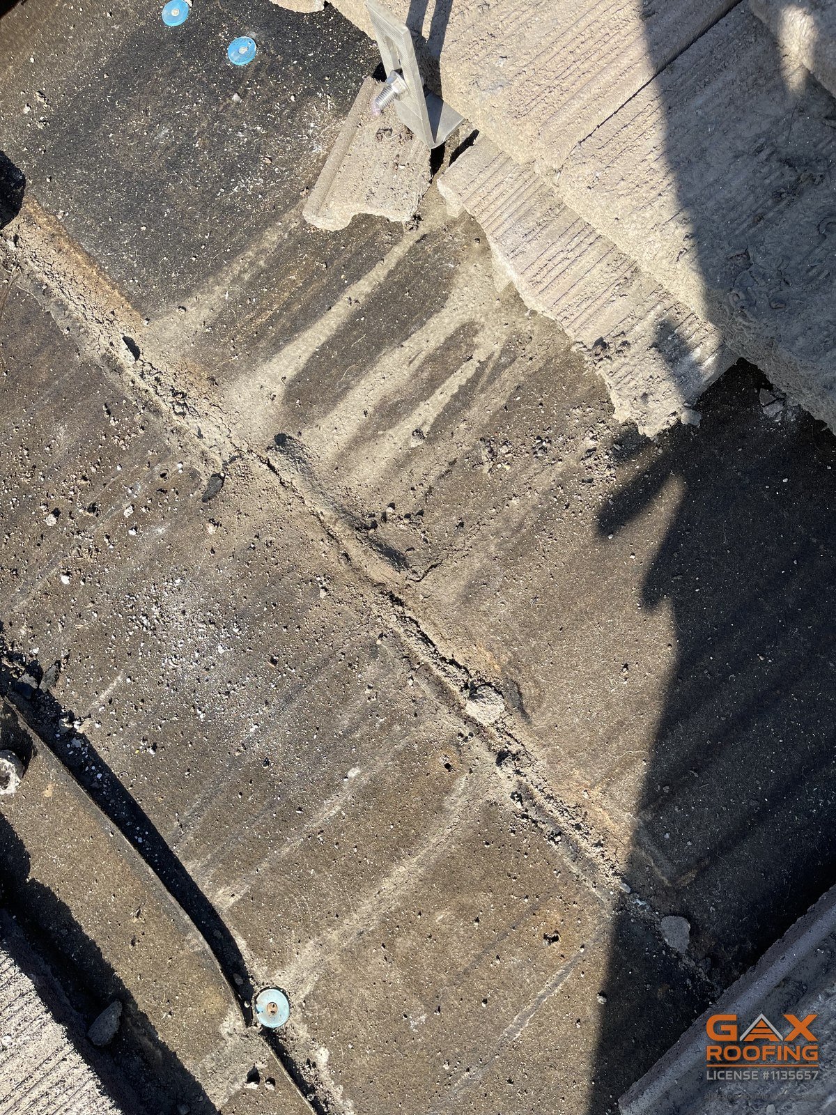 Cracked concrete tile and mounting hardware beside a conduit run on a San Dimas solar roof