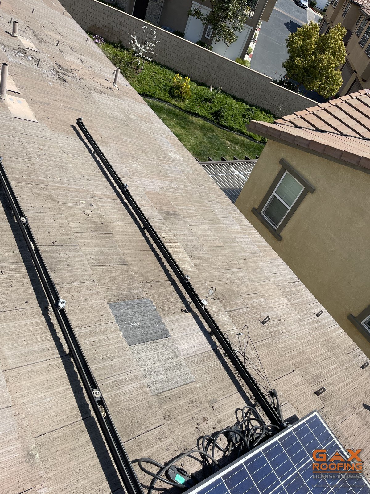 Conduit runs and a solar panel on a concrete tile roof during a solar reset by GAX Roofing