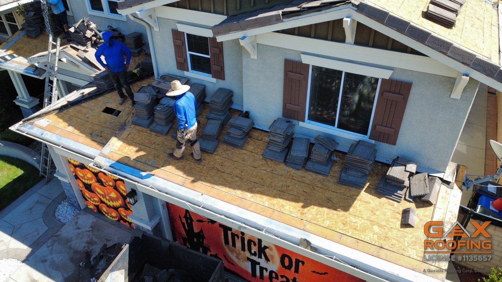 Cuadrilla de GAX Roofing apilando teja de concreto en un techo bajo durante un levantamiento y recolocaci&oacute;n en Rancho Cucamonga