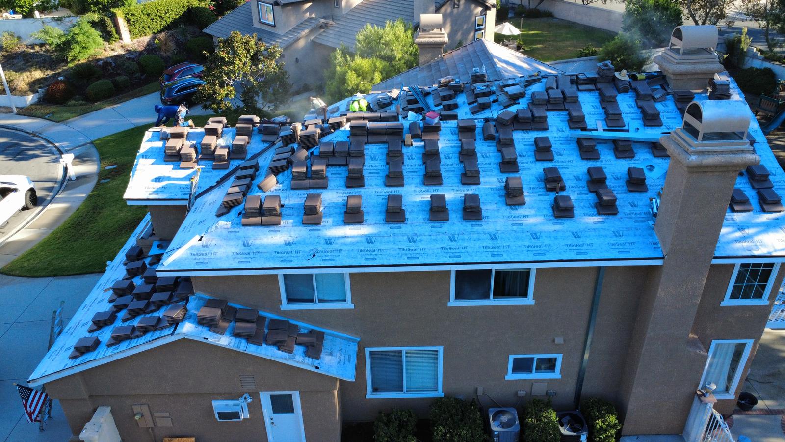 Vista lateral de una casa en Etiwanda a mitad de un reemplazo de teja, con teja nueva en cada agua