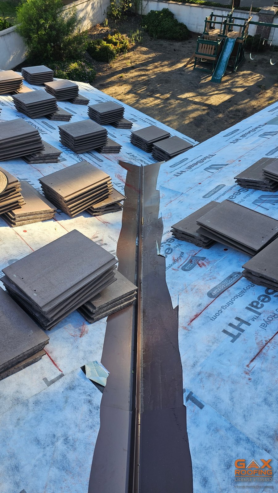 New metal valley with Eagle concrete tile stacked on both sides during a tile replacement by GAX Roofing in Rancho Cucamonga, CA