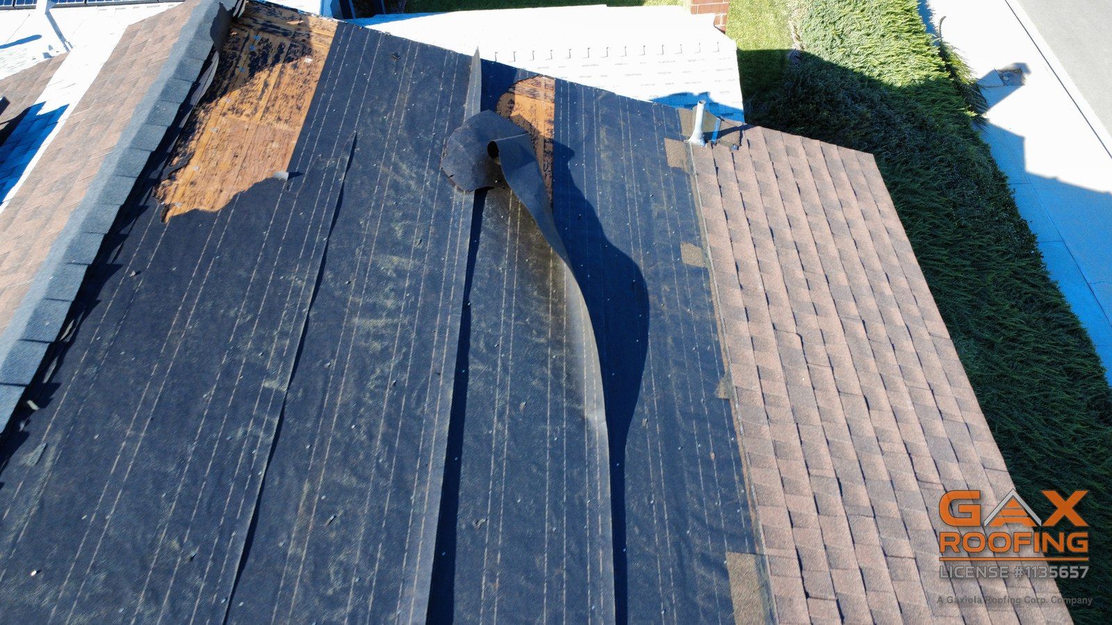 Shingle roof slope with shingles blown off by Santa Ana winds, old felt torn and the deck showing, Rancho Cucamonga