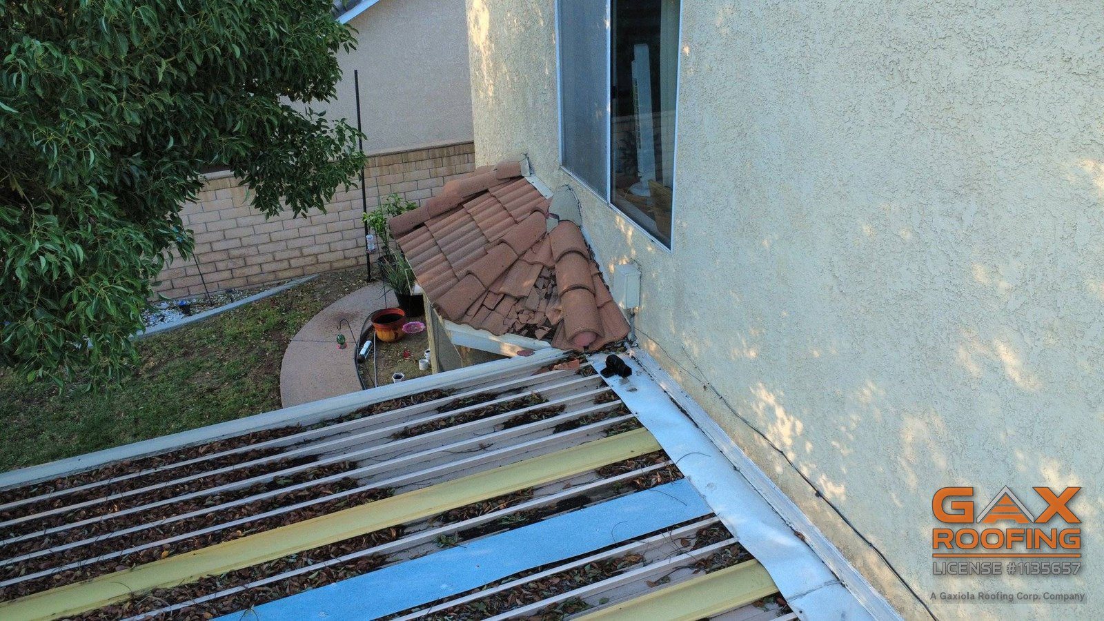 Broken concrete tile piled on a first-story tile roof against the wall of a house in Upland, after wind knocked tile down from the second story