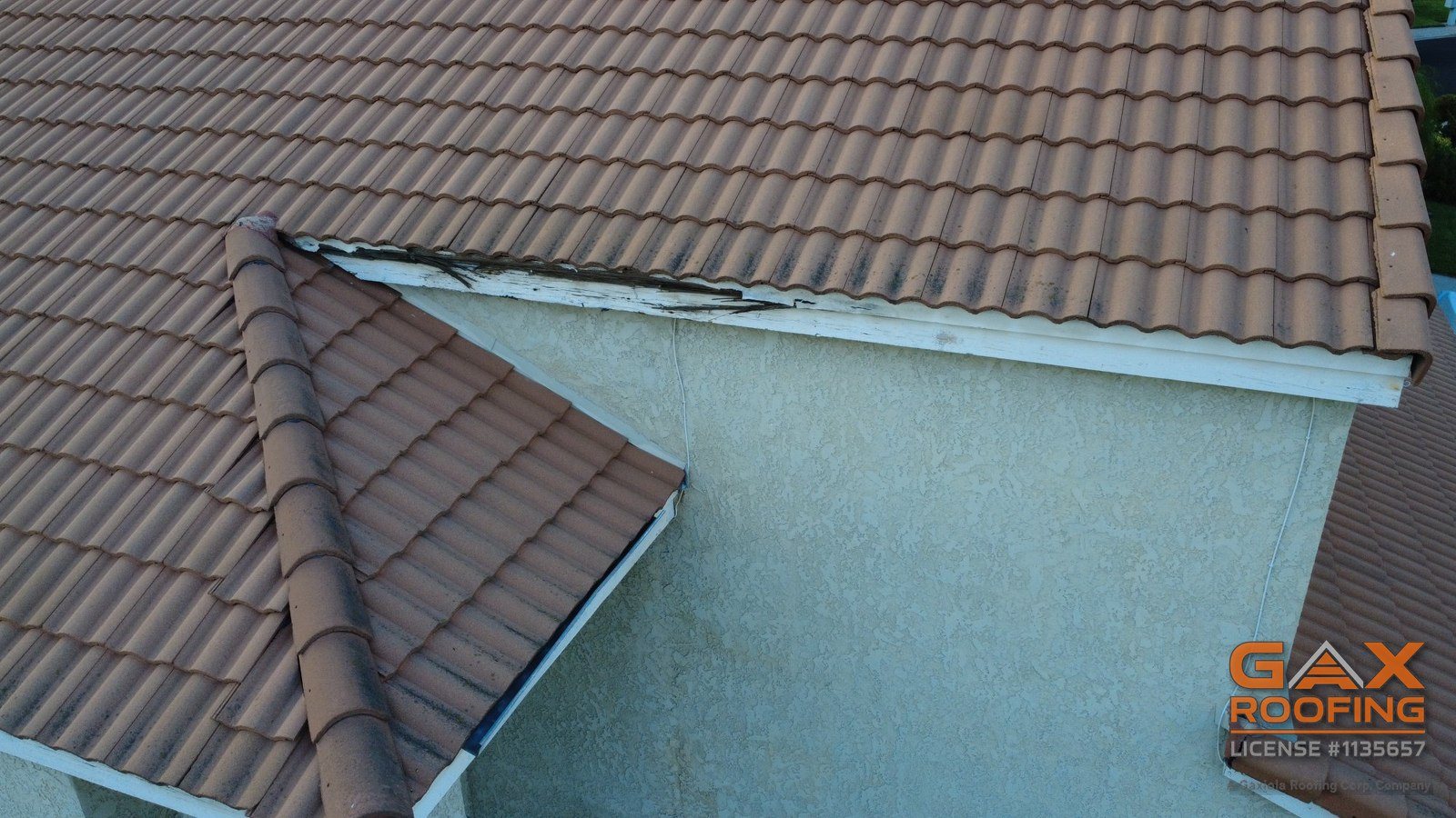 Second-story concrete tile roof edges above a lower roof, with a cracked tile at the corner, Upland